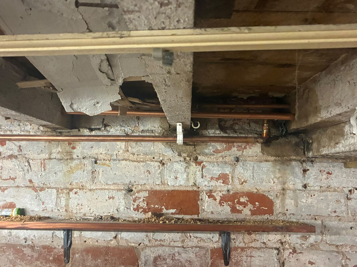 New copper flow and return pipe work clipped into floor joists above a brick cellar wall