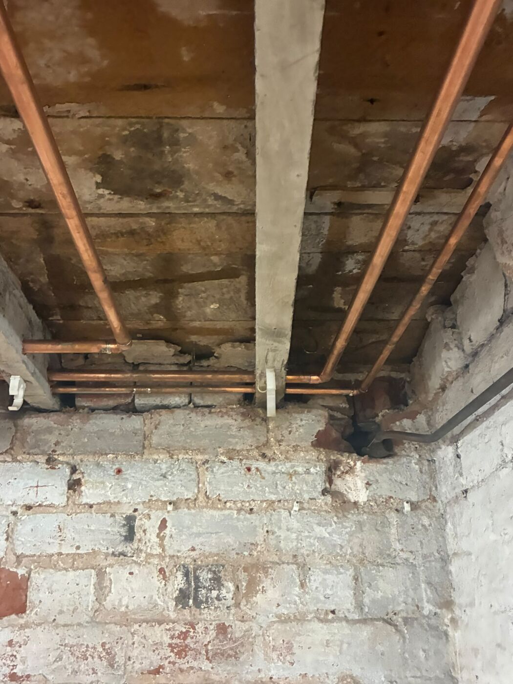 Copper heating pipe work running neatly between exposed timber joists